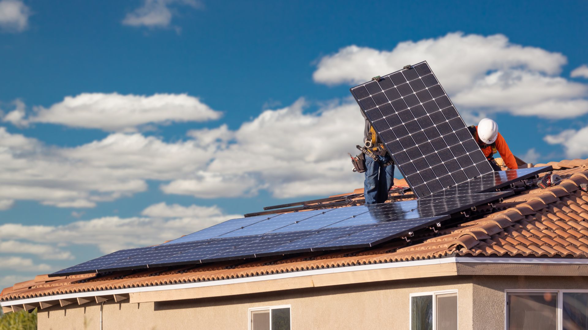 A man working on a solar panel on the roof of a house